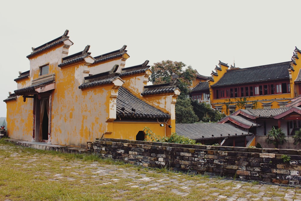 a yellow building with a stone wall in front of it