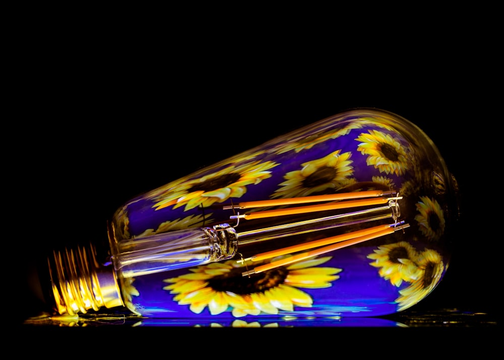 a yellow and blue glass light bulb on a black background