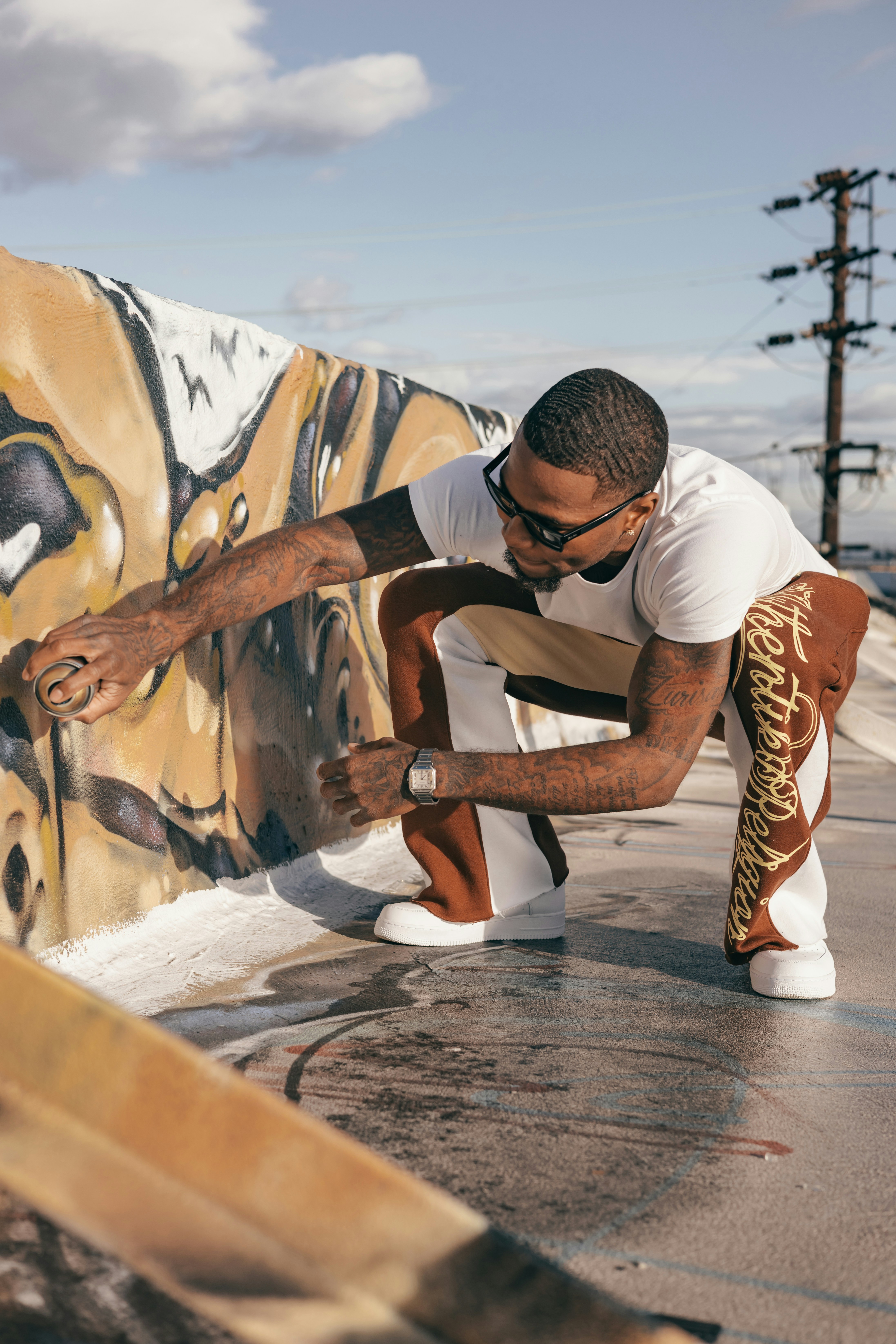 a man kneeling down next to a wall with graffiti on it