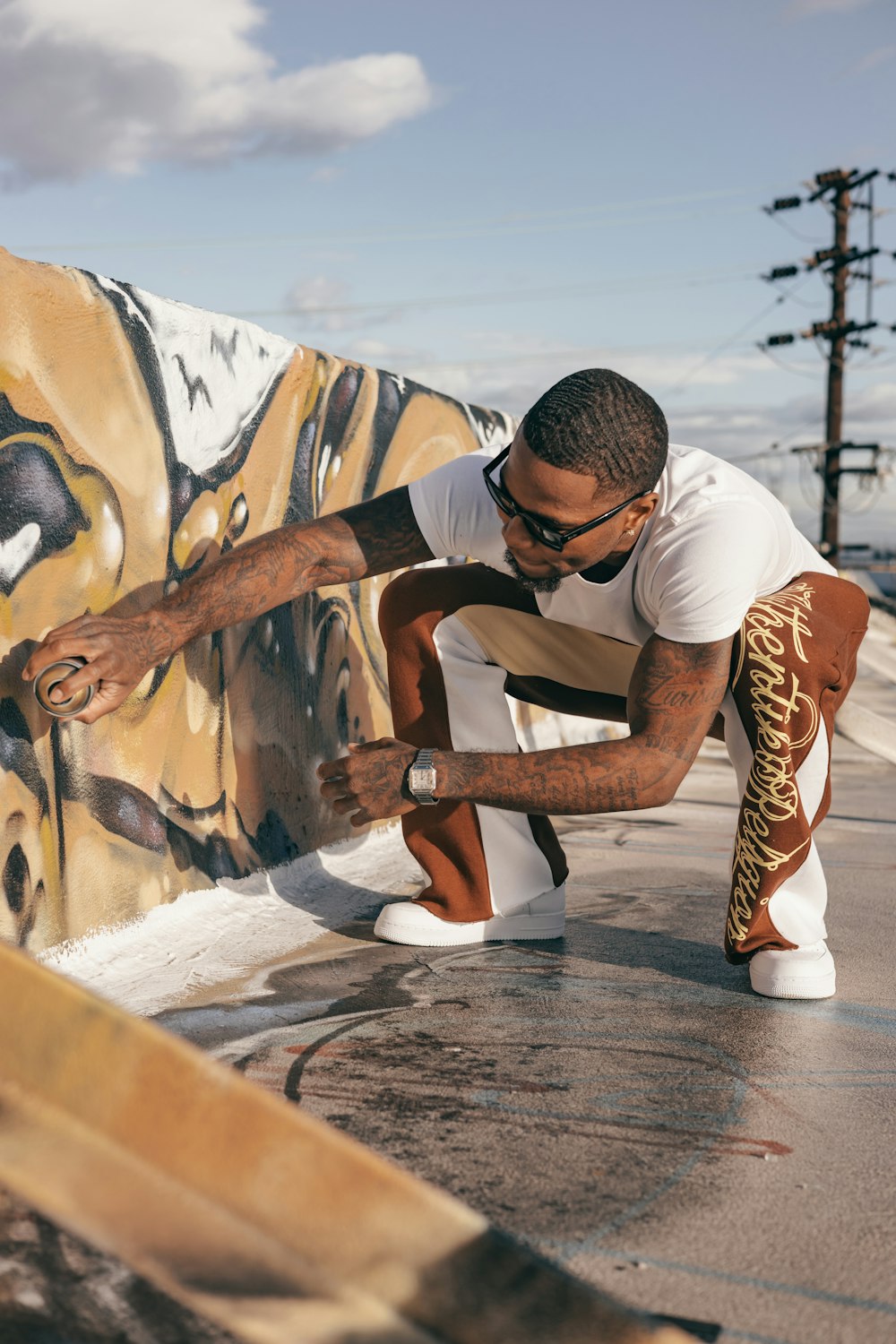 a man kneeling down next to a wall with graffiti on it