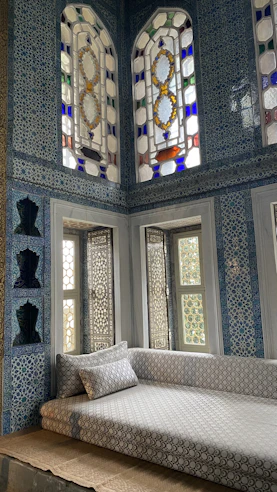 Sunlit lounge with vibrant cushions and intricate tilework.