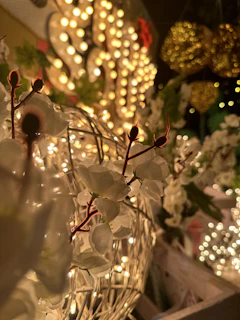 A close-up of intricate floral decorations intertwined with fairy lights at an evening event.
