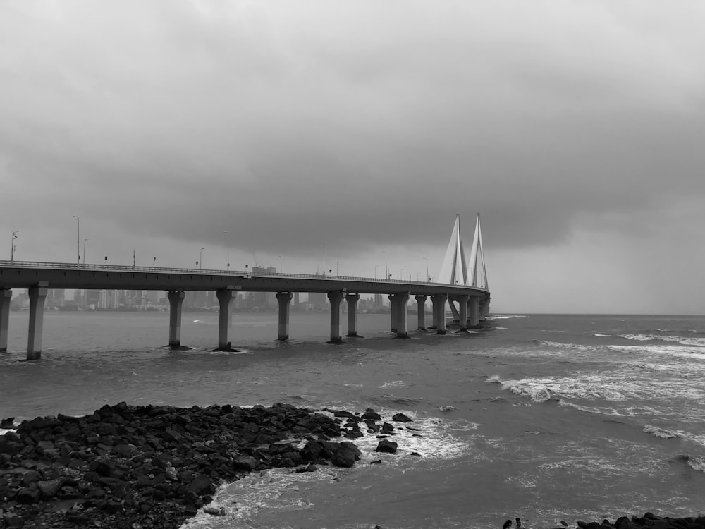 a black and white photo of a bridge over the ocean