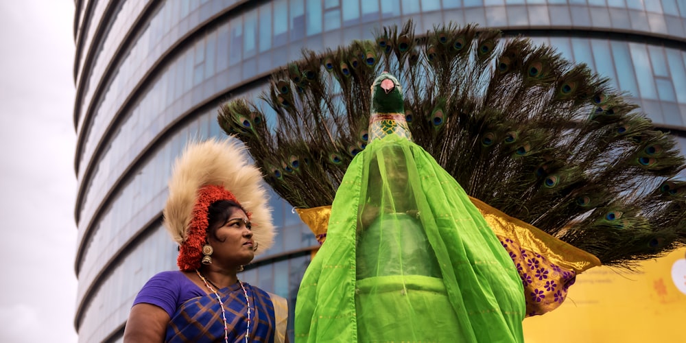a woman in a green dress and headdress standing next to a tall building