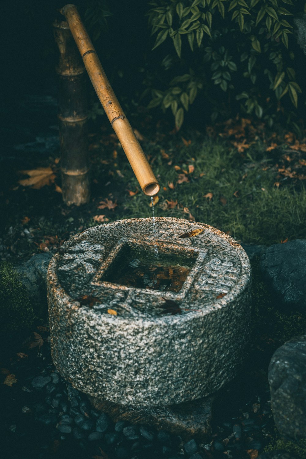 a stone bowl with a bamboo stick sticking out of it