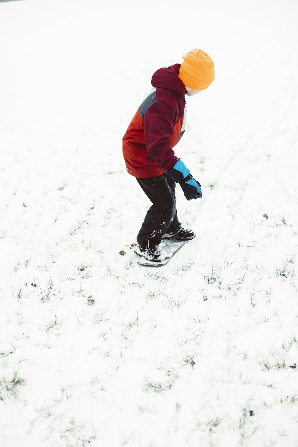Ein kleiner Junge fährt mit dem Snowboard einen schneebedeckten Hang hinunter