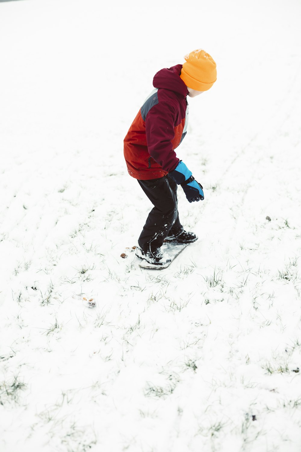 a young boy riding a snowboard down a snow covered slope