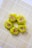 Five pieces of yellow dumplings with a filling that appears to contain minced meat and small orange carrot cubes, arranged neatly on a bamboo sushi mat. The dumplings are placed in a circular pattern, creating an aesthetically pleasing presentation.
