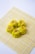Four yellow dumplings with visible filling are placed on a bamboo mat against a plain background. Each dumpling is garnished with a small piece of carrot.