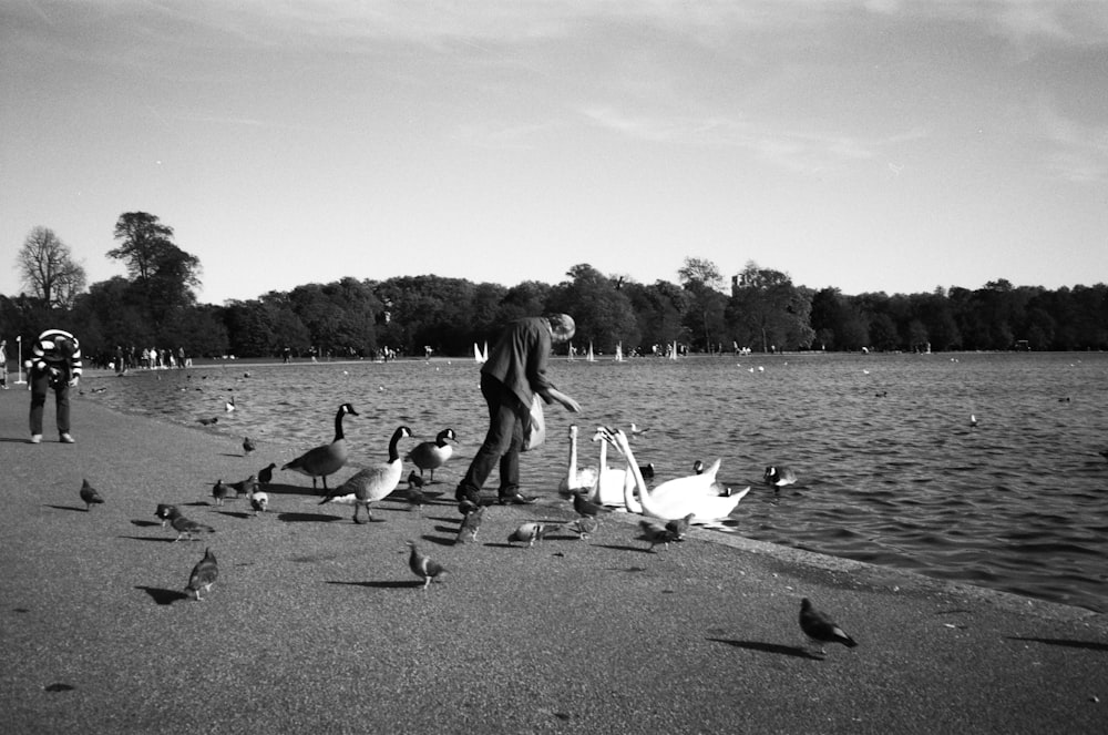 a black and white photo of a man feeding a flock of birds