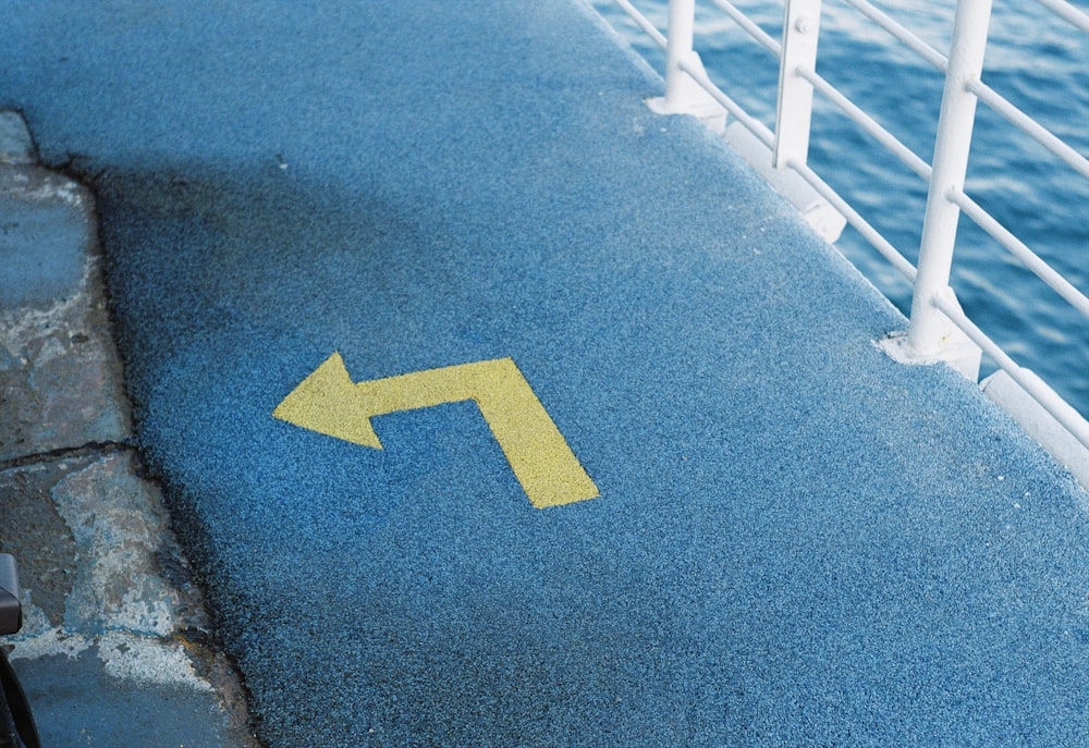 a yellow arrow painted on the ground next to a railing