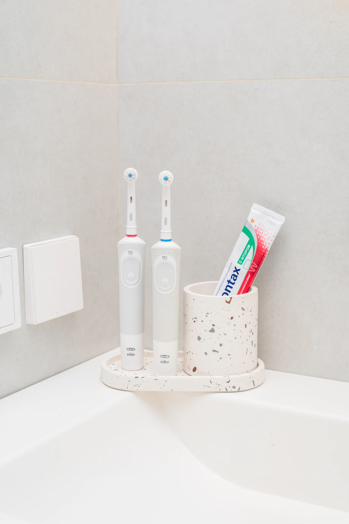Electric toothbrushes and oral-care products arranged beside a bathroom sink