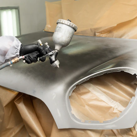 a person in white gloves and white gloves painting a car