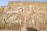 Ancient Egyptian hieroglyphics and carvings depicting figures of deities and historical figures. Intricate symbols and artwork are etched into the stone, showcasing traditional Egyptian attire and accessories.