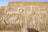 Ancient Egyptian hieroglyphics and carvings depicting figures of deities and historical figures. Intricate symbols and artwork are etched into the stone, showcasing traditional Egyptian attire and accessories.
