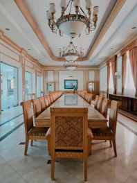 A grand dining table crafted from walnut wood, surrounded by matching chairs in a warmly lit traditional dining room.