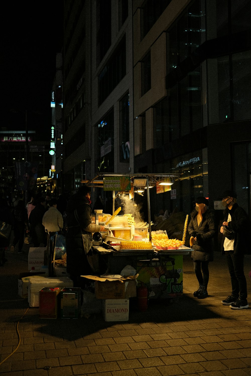 Un hombre y una mujer parados frente a un puesto de comida por la noche