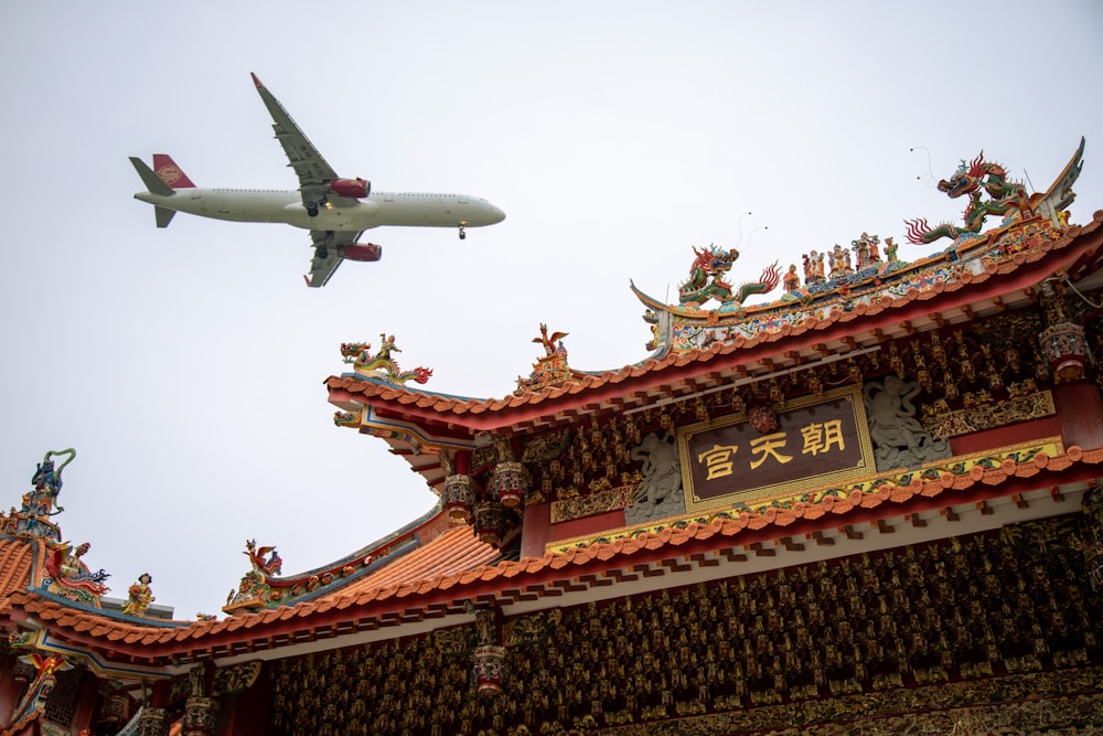 an airplane is flying over a chinese building