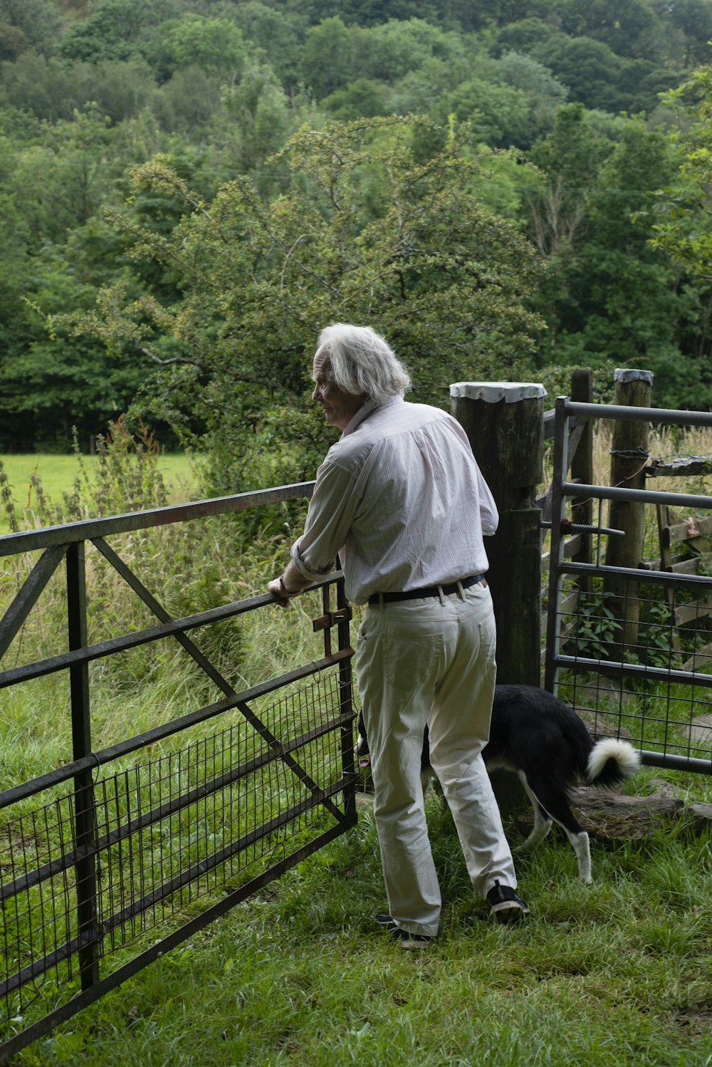 a man standing next to a fence with a dog