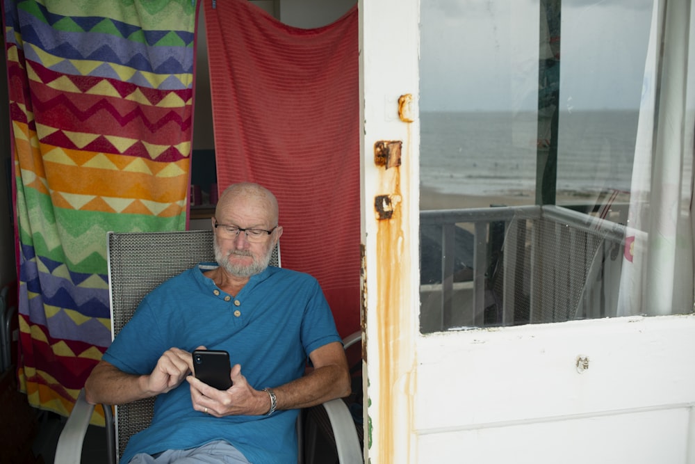 a man sitting in a chair looking at a cell phone