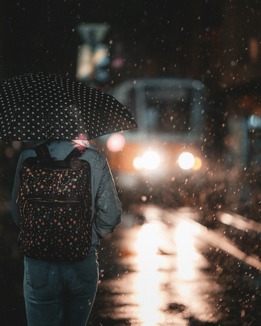 a person with a backpack and umbrella walking in the rain