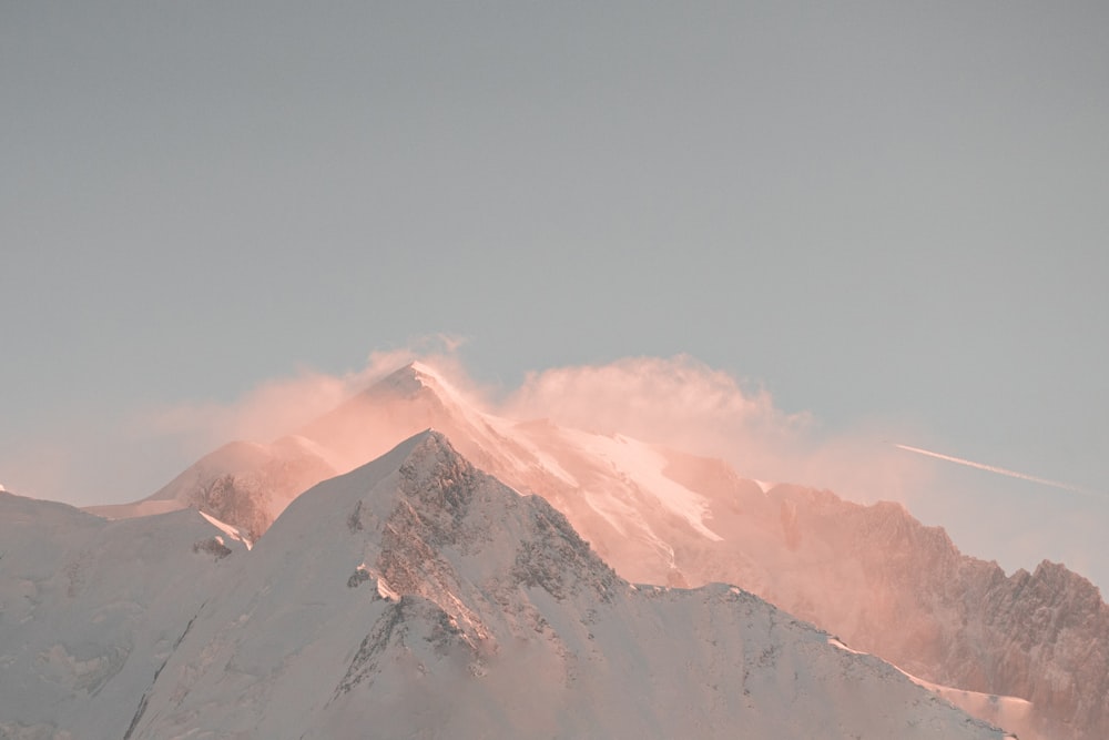 a mountain covered in snow under a cloudy sky