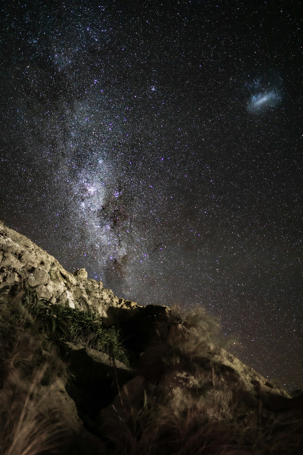 the night sky with stars above a mountain