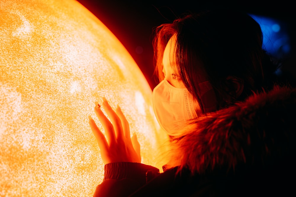 a woman wearing a face mask holding a large sun