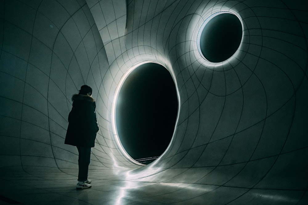 a woman standing in front of a tunnel in a dark room