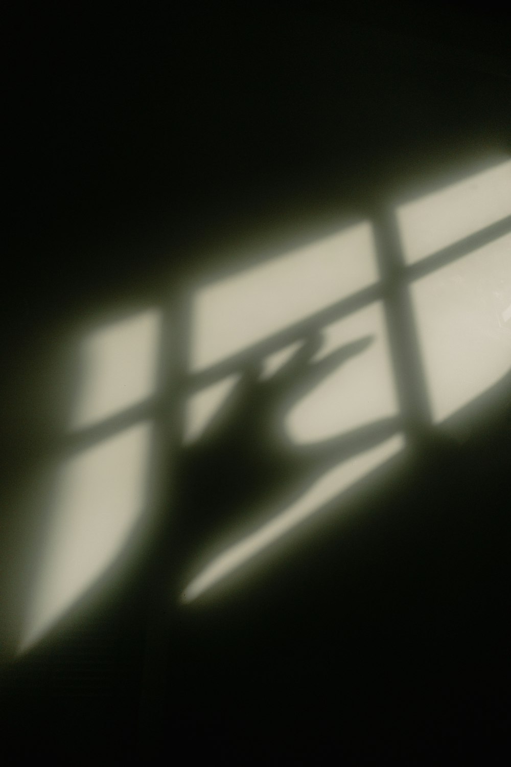 the shadow of a person's hand on a window sill