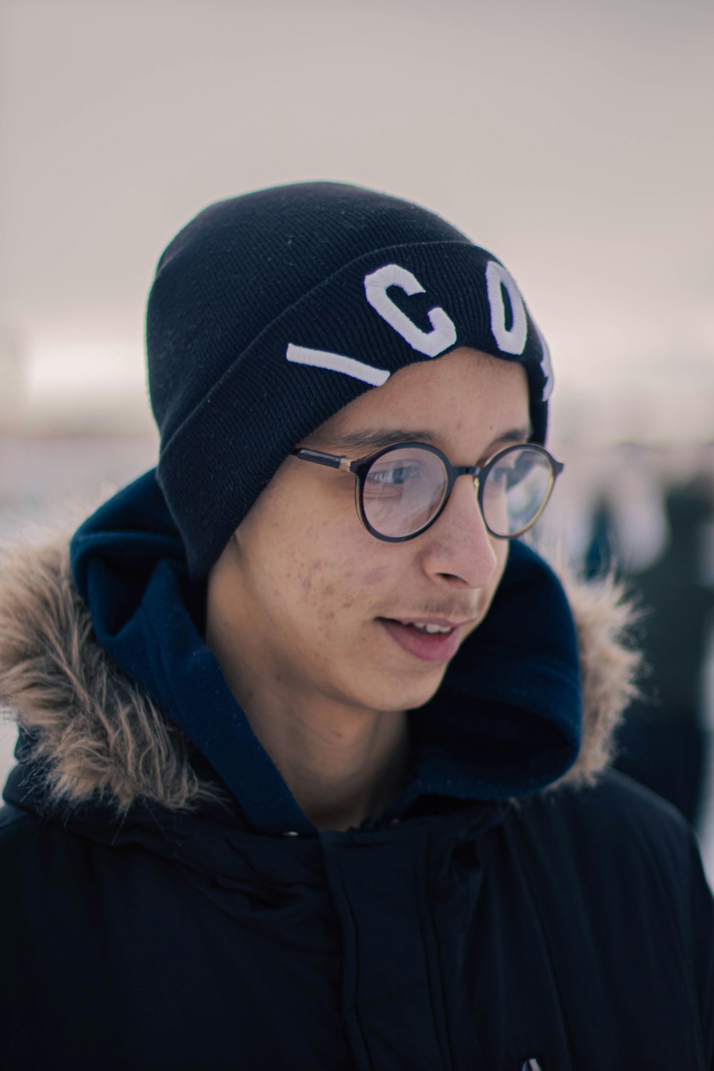 a young man wearing a beanie and glasses