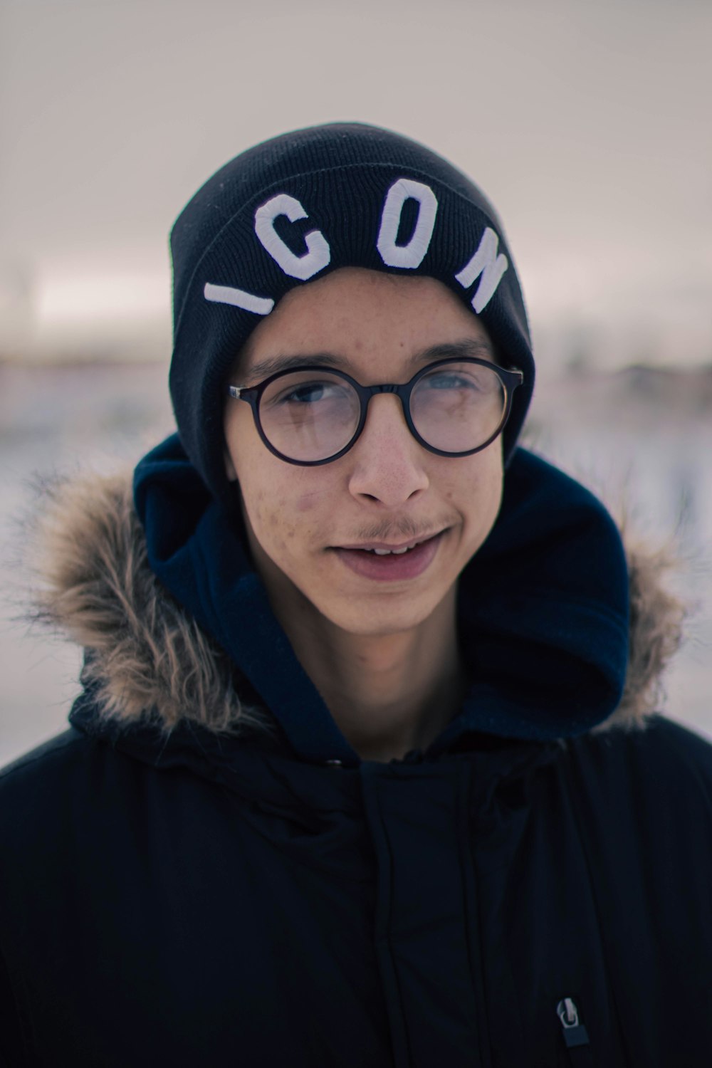 a young man wearing glasses and a beanie