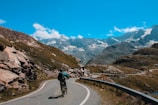 A cyclist riding along a winding country road under clear blue skies.
