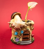 a small figurine of a mushroom house with a flower growing out of it