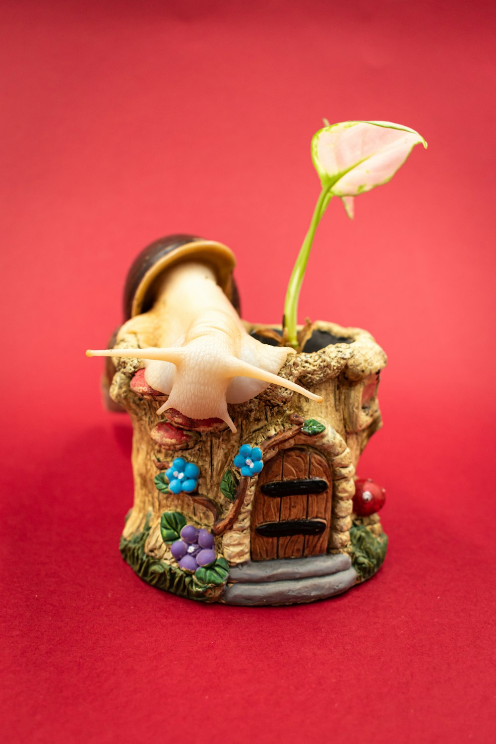 Una pequeña estatuilla de una casa de hongos con una flor que crece fuera de ella