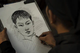 An artist's hand sketching a detailed portrait on textured paper.