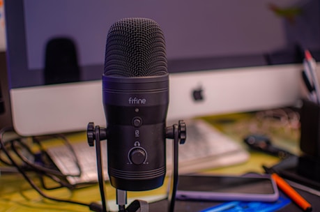 A microphone surrounded by sheet music and creative studio equipment.