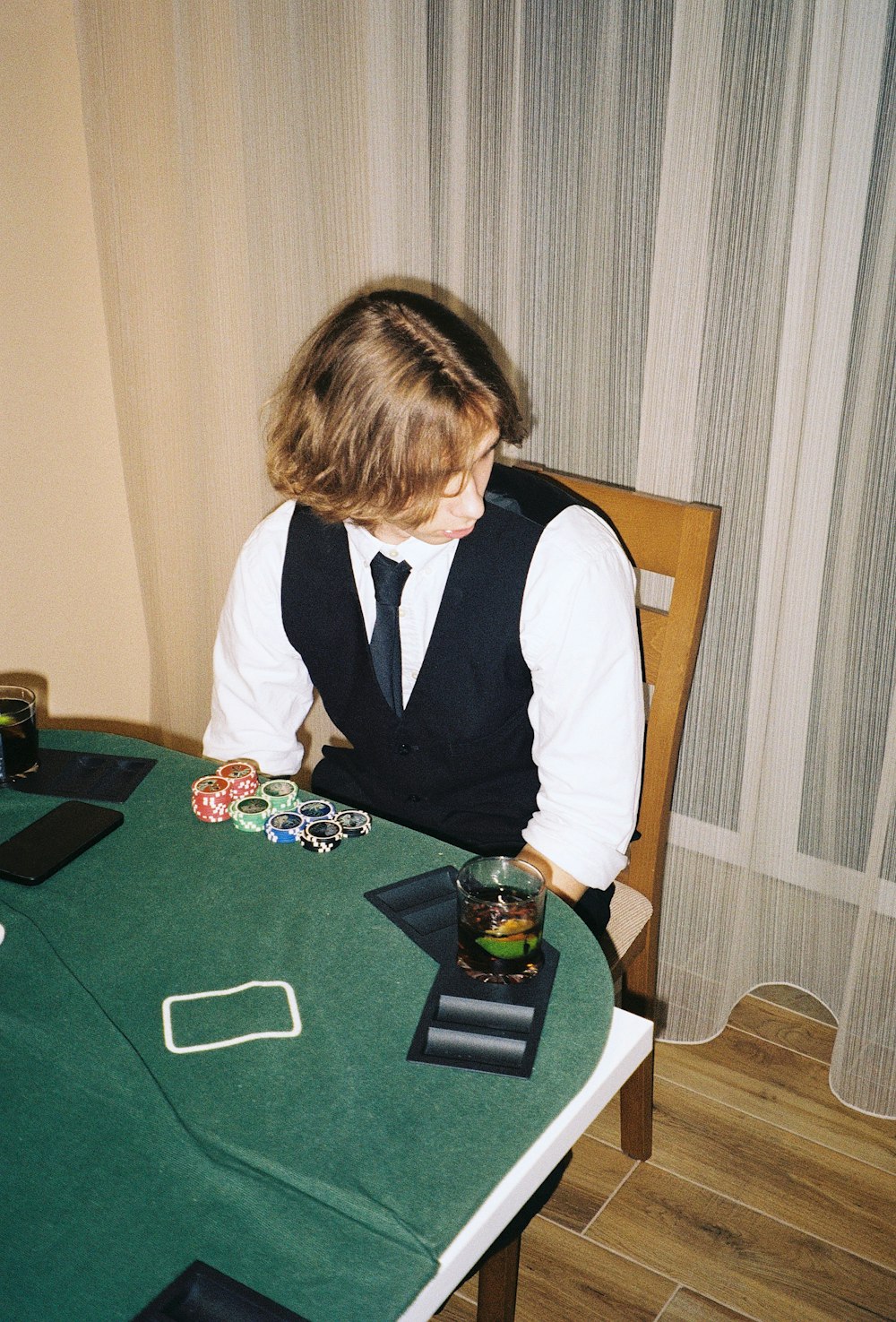 a young boy sitting at a green table with cards