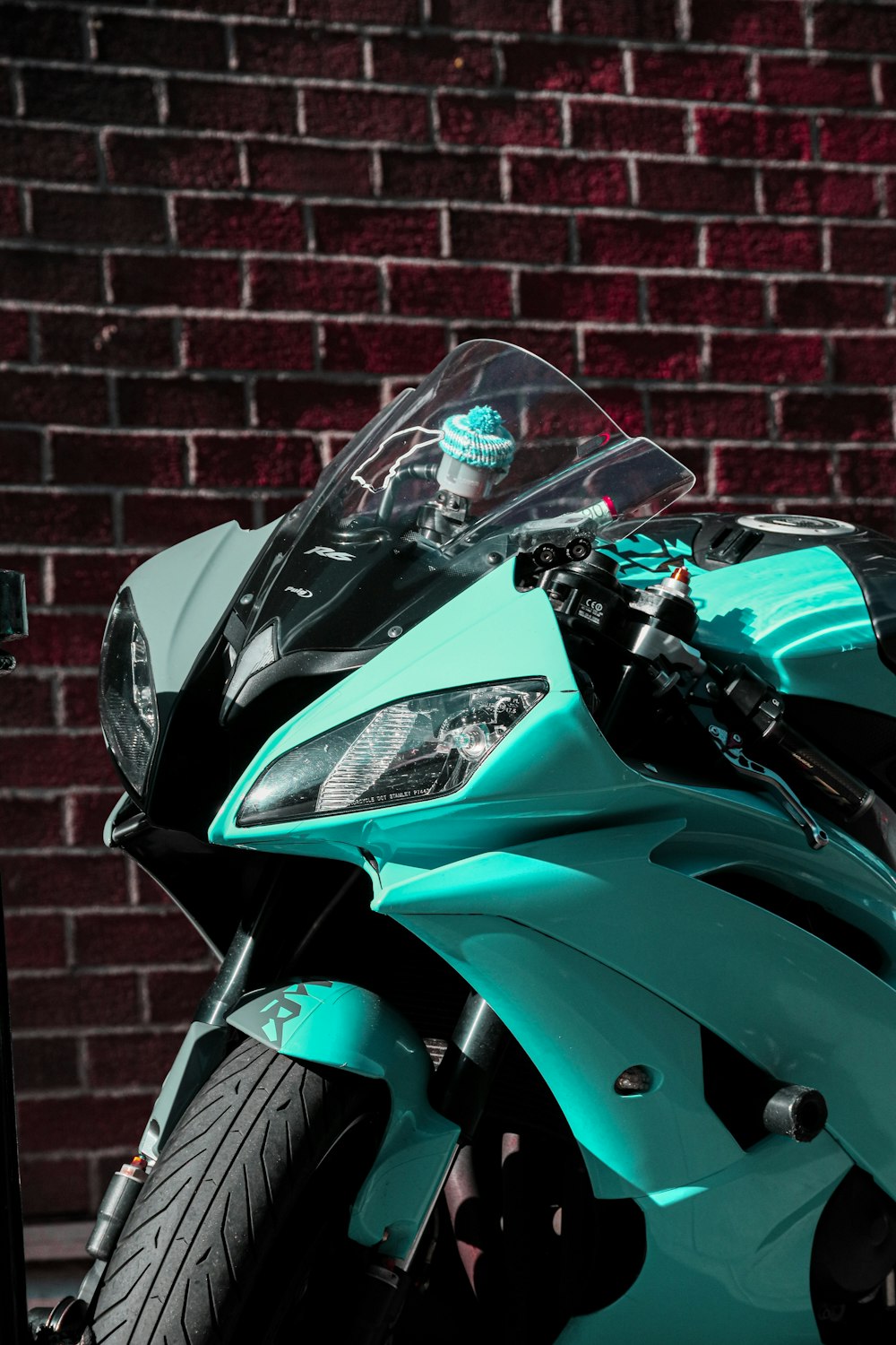 a blue motorcycle parked in front of a brick wall