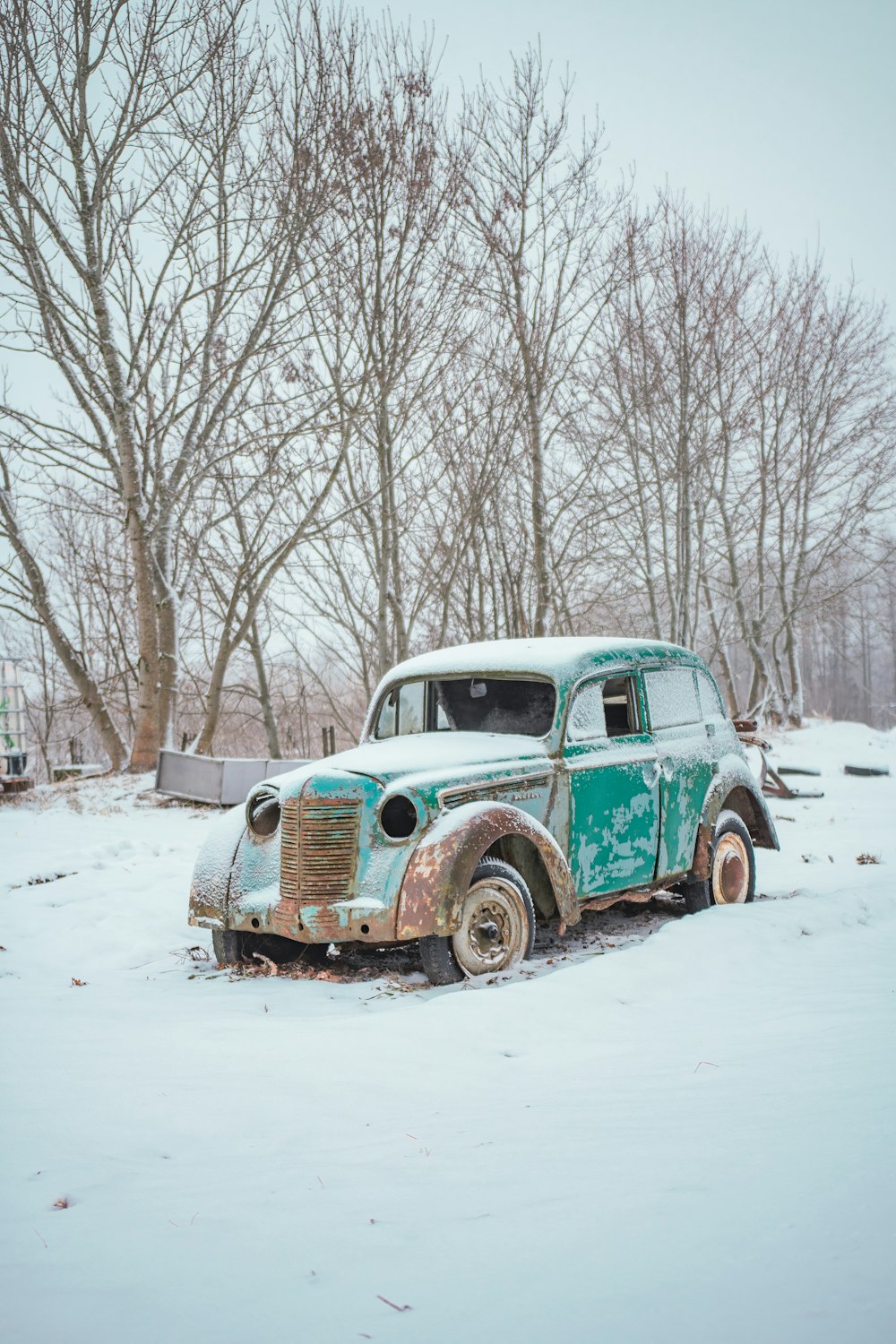 an old rusty truck sitting in the snow