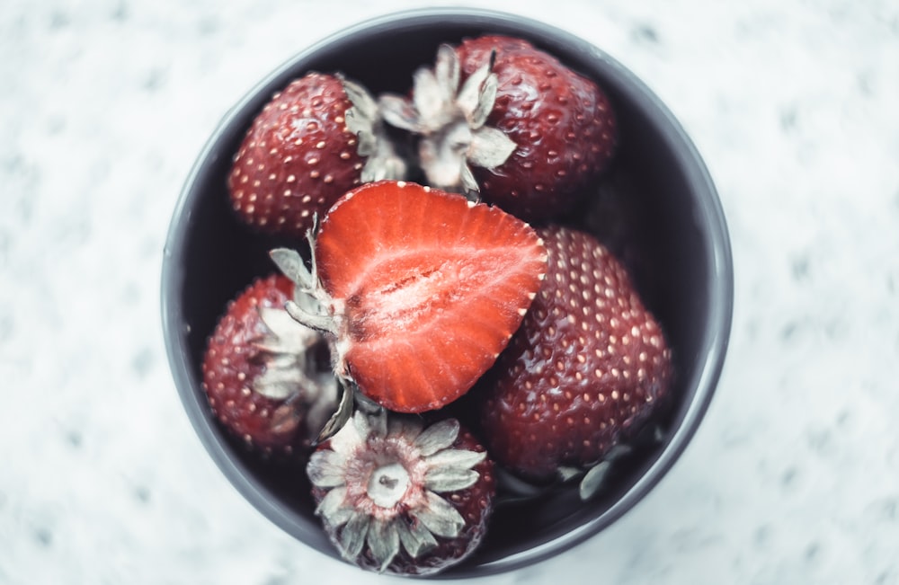 a bowl filled with strawberries and flowers on top of a table