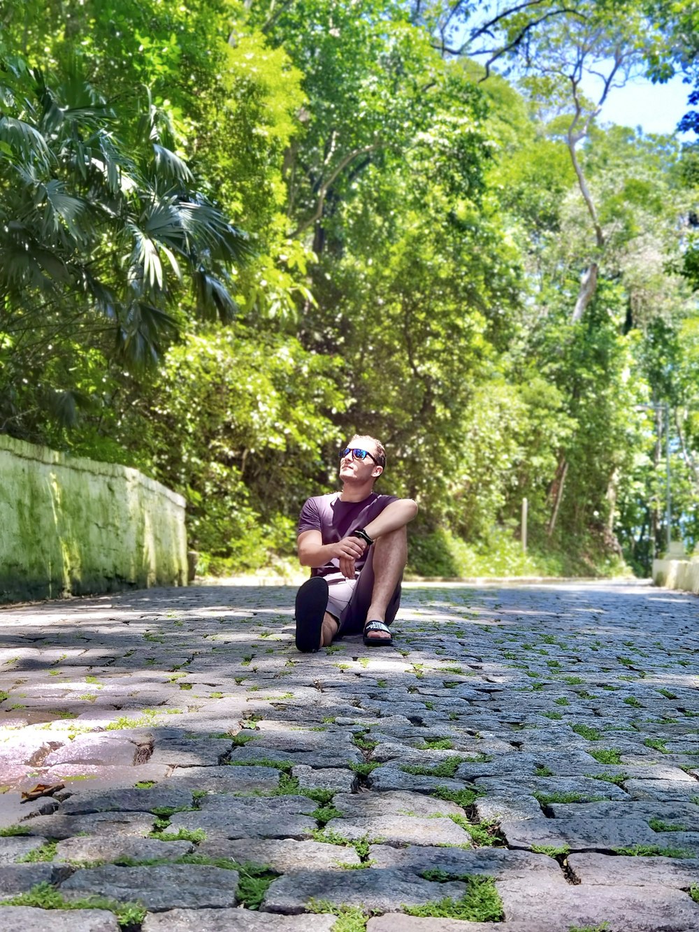 a man is sitting on a cobblestone road