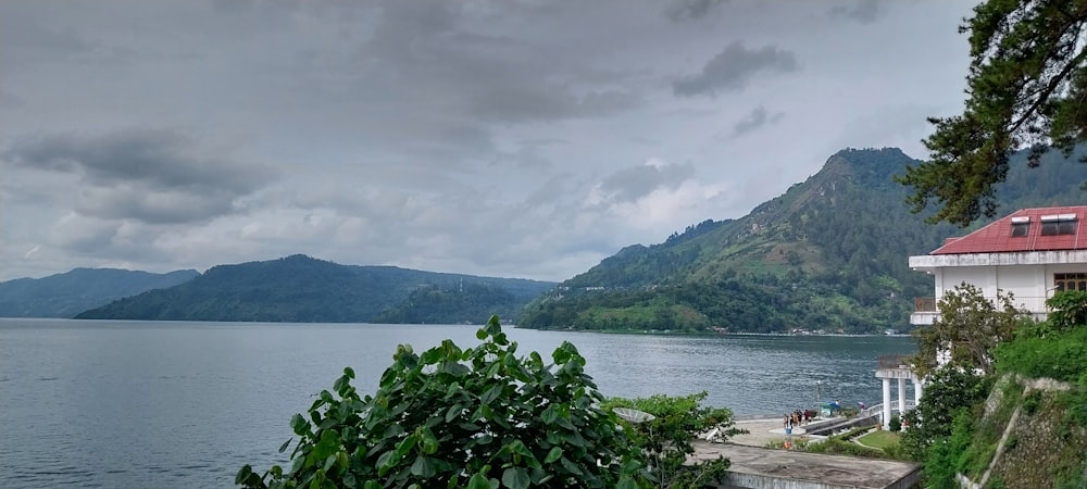 a house on the edge of a lake with mountains in the background