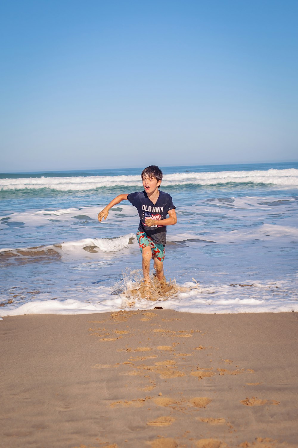 a young boy is playing in the water at the beach