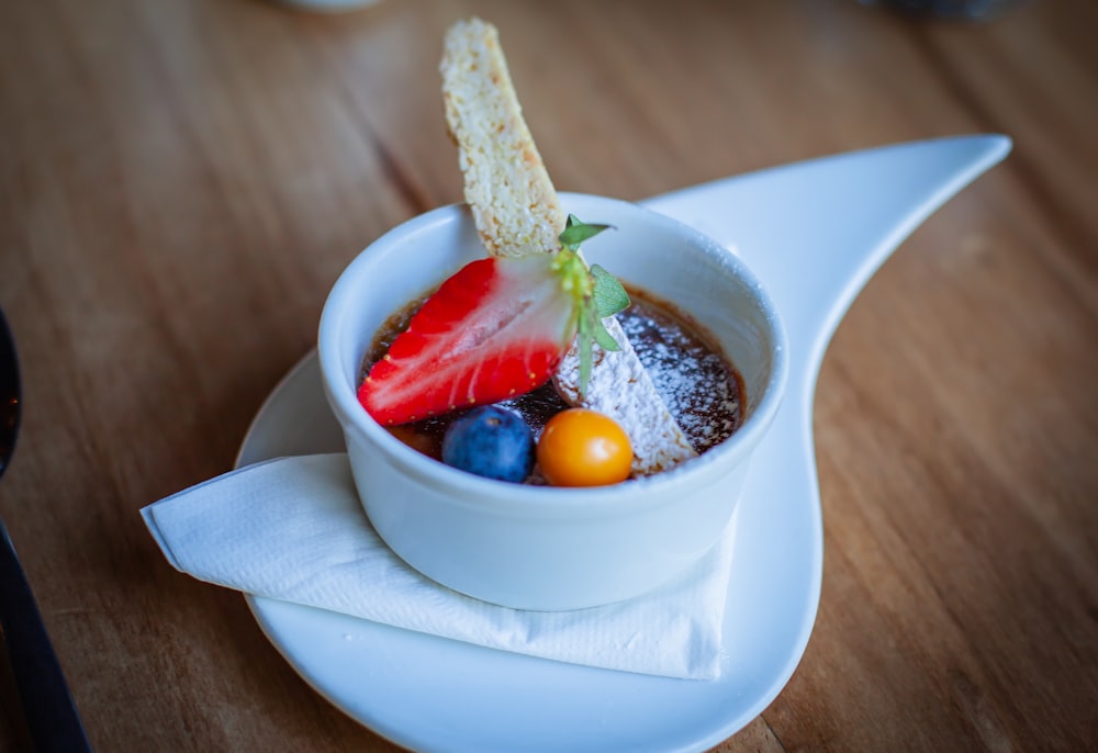 a bowl of fruit and bread on a white plate