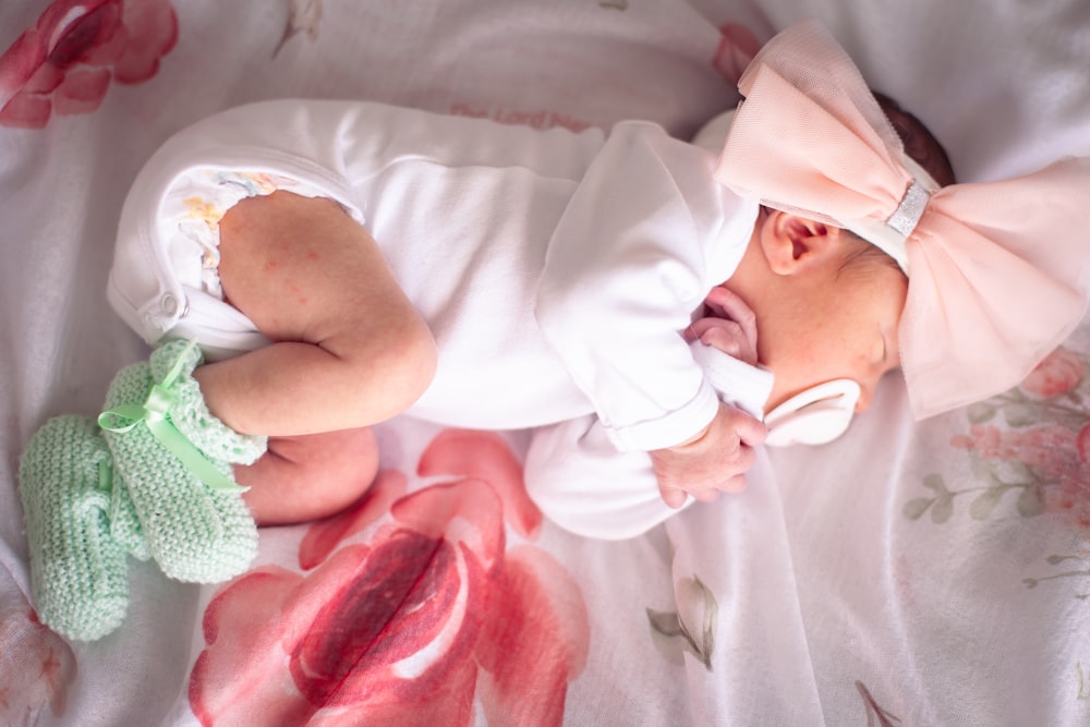 a baby laying on its back with a pink bow on it's head