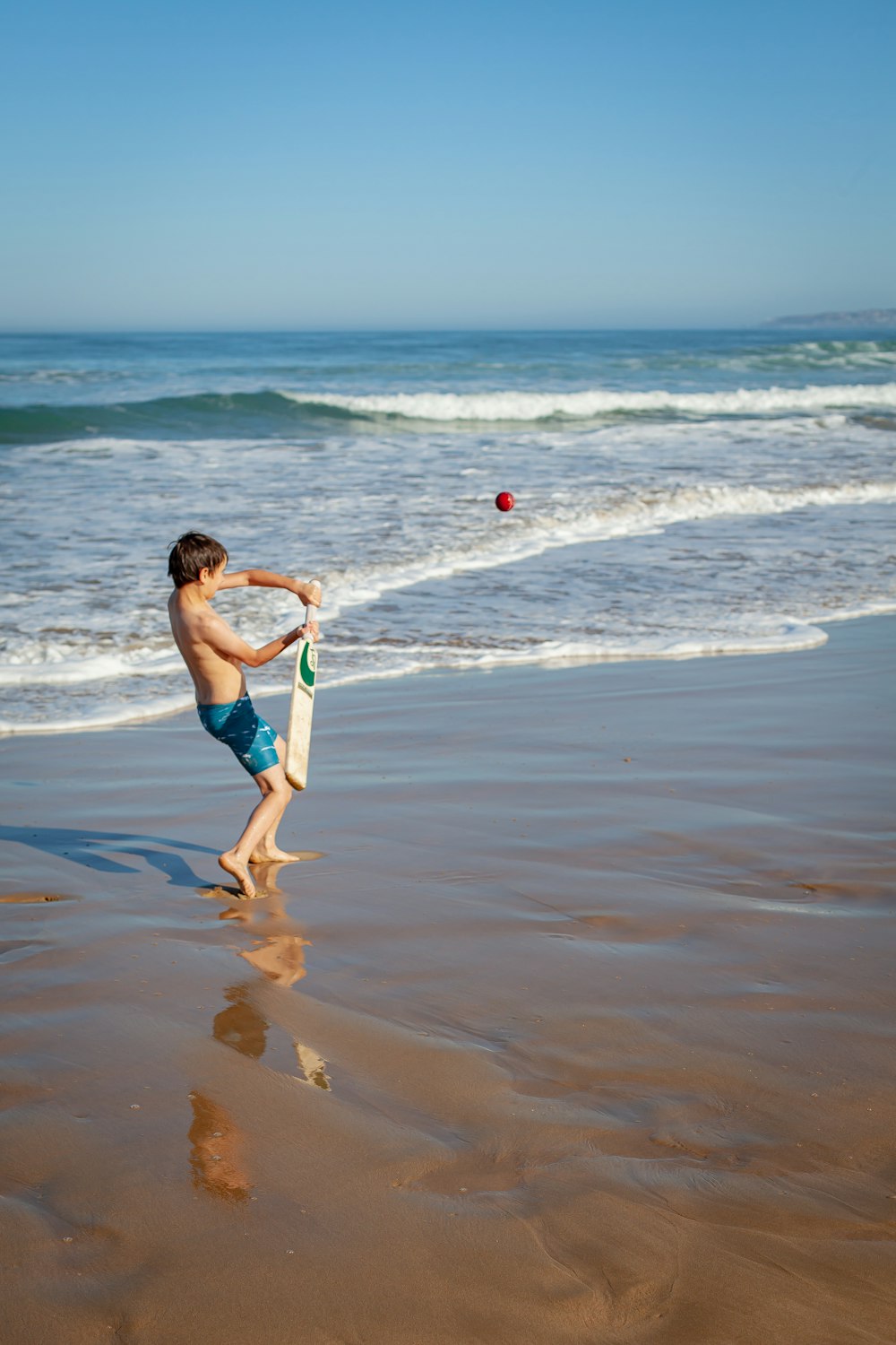 a young boy standing on top of a sandy beach