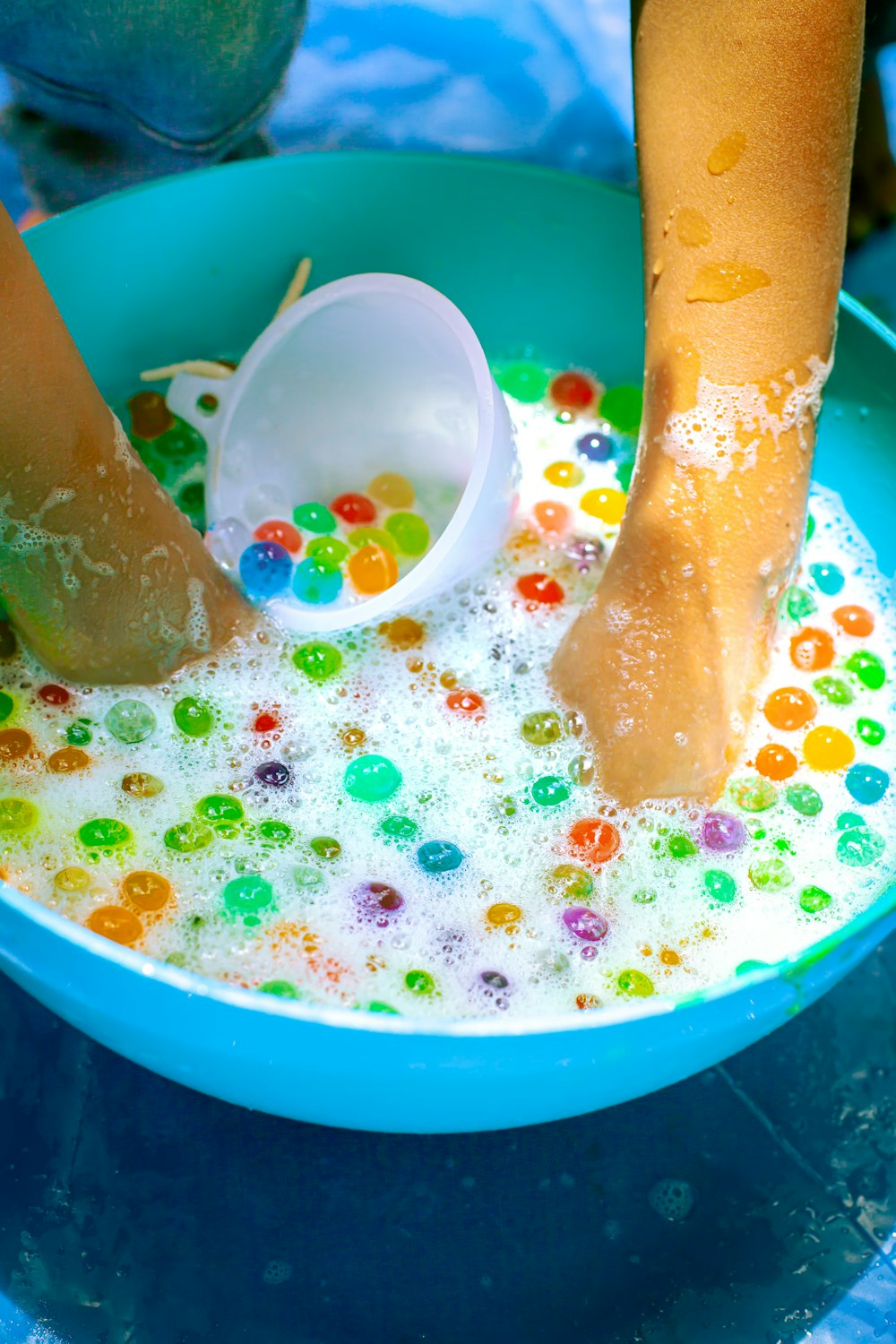 a child's feet in a bowl of water with gummy bears