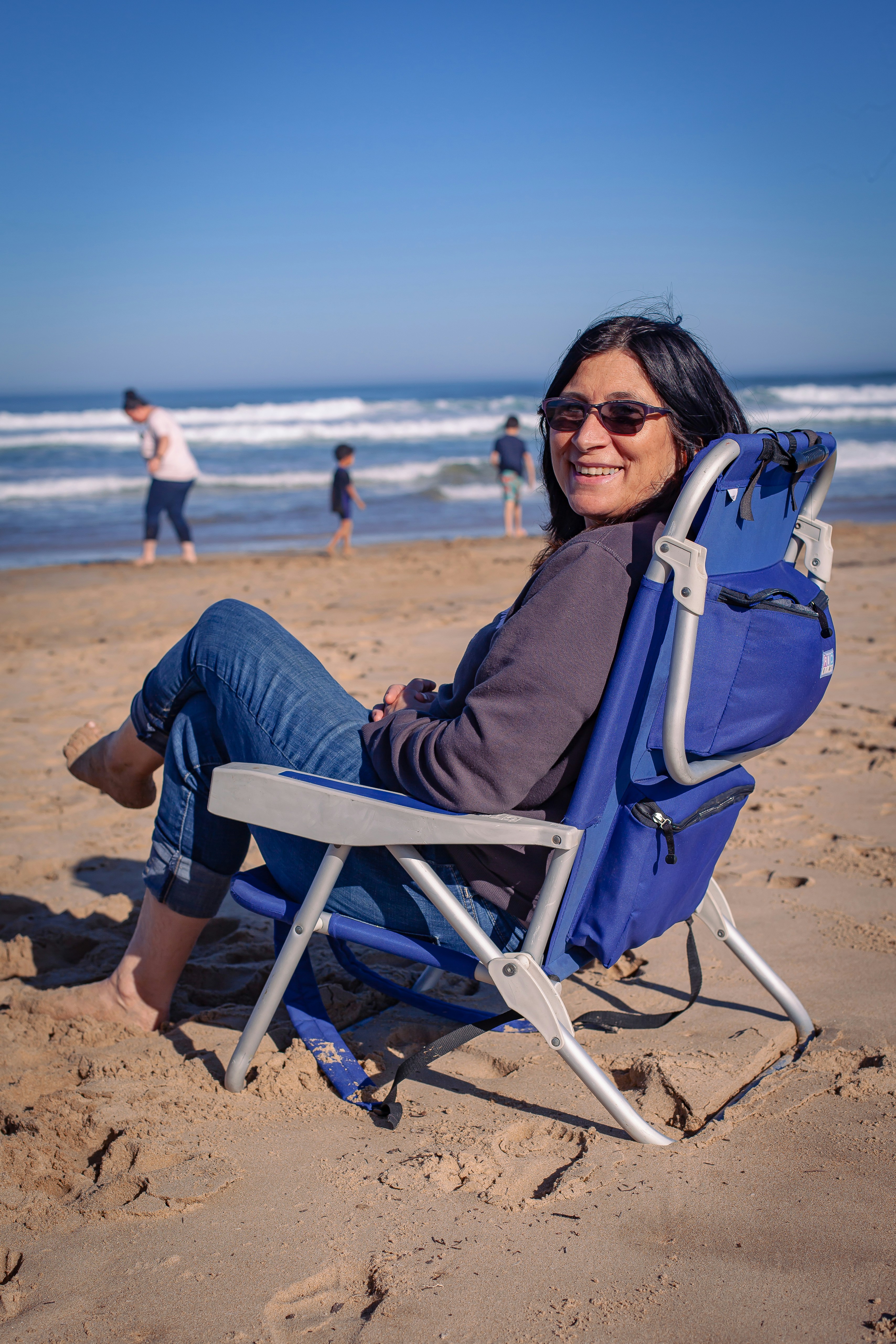a woman sitting in a chair on the beach