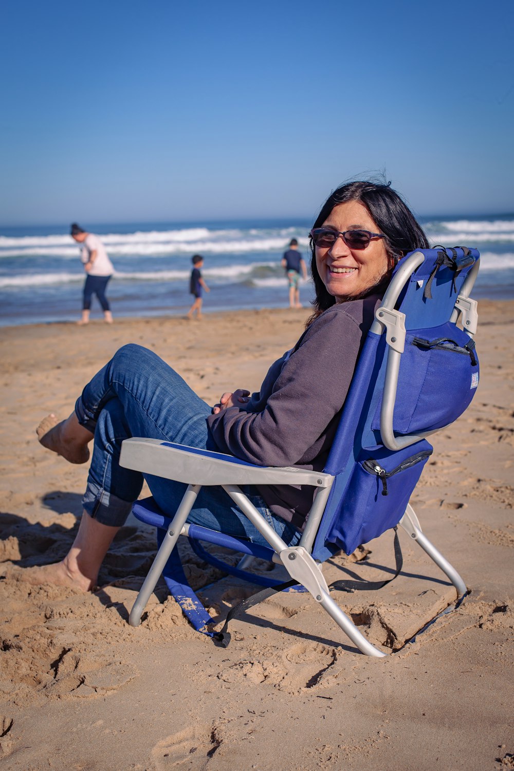 a woman sitting in a chair on the beach